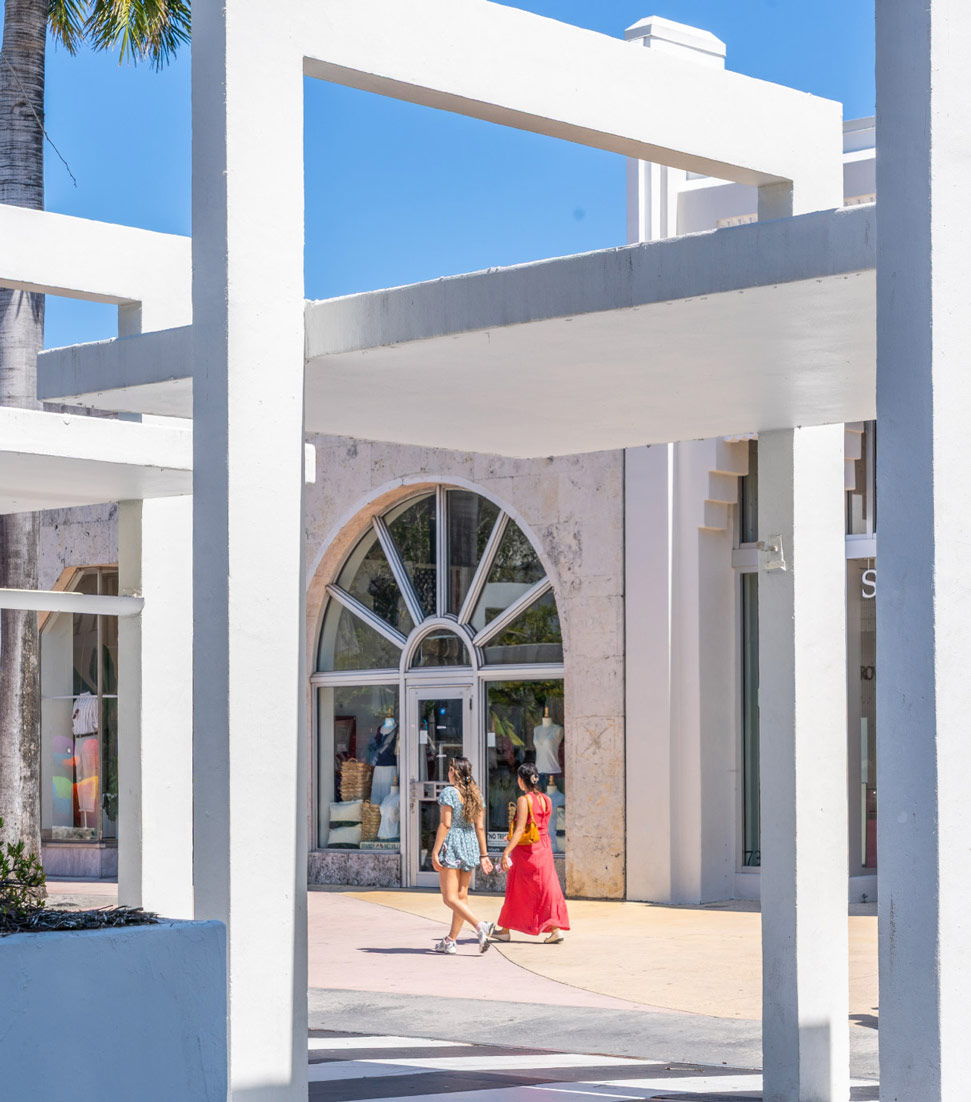 Two women walking past a large arched storefront