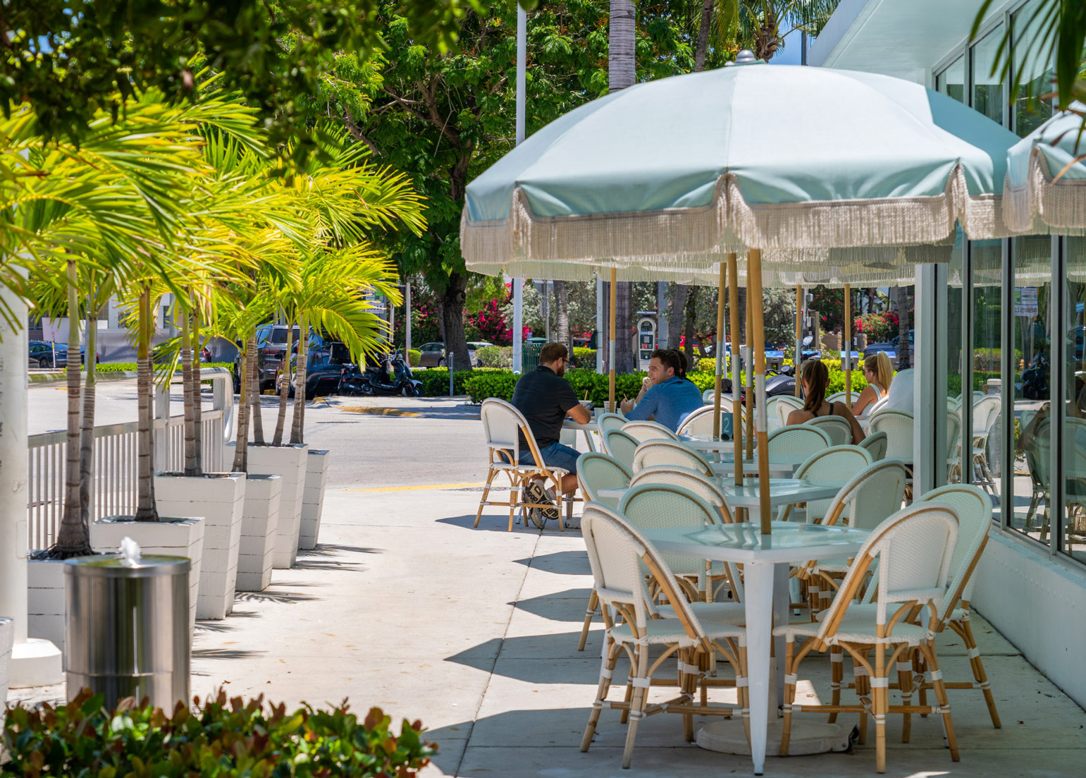 An Apple Store with a stone façade & glass entrance framed by palm trees